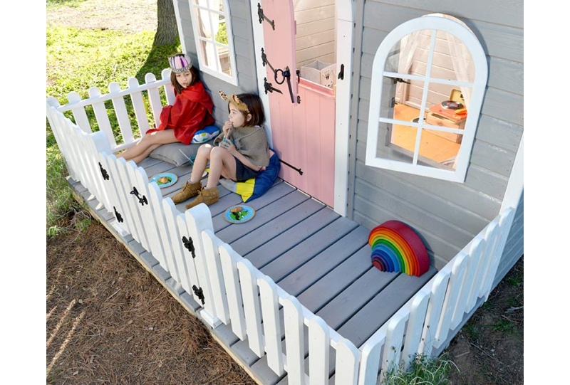Kinder spielen in einer holzernen Spielhütte im Freien