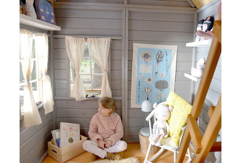 Kinder spielen in einer holzernen Spielhütte im Freien