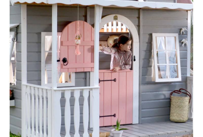 Kinder spielen in einer holzernen Spielhütte im Freien