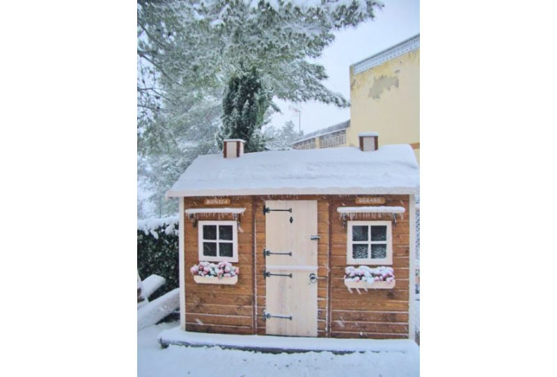 Kinder spielen in einer holzernen Spielhütte im Freien