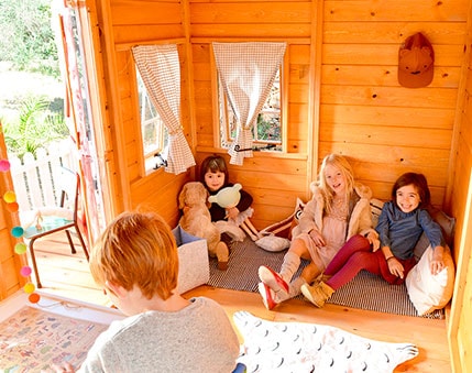 Kinder spielen in einer holzernen Spielhütte im Freien