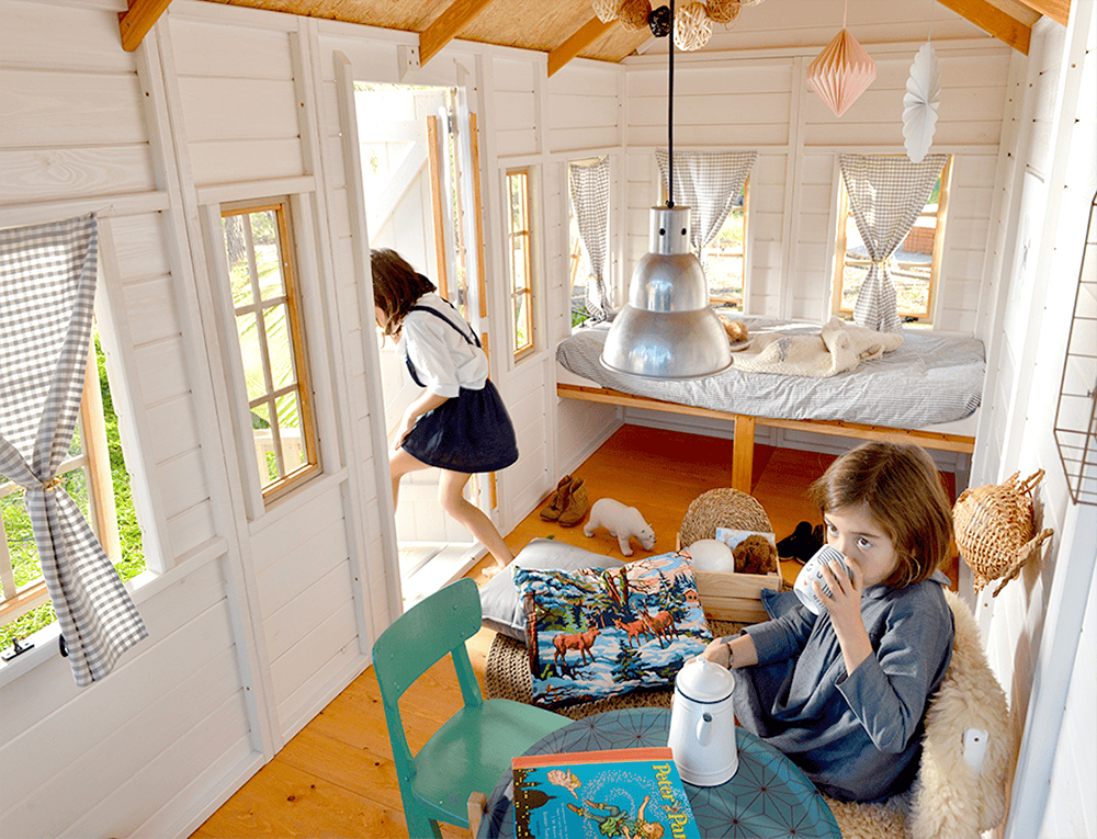 Kinder spielen in einer holzernen Spielhütte im Freien