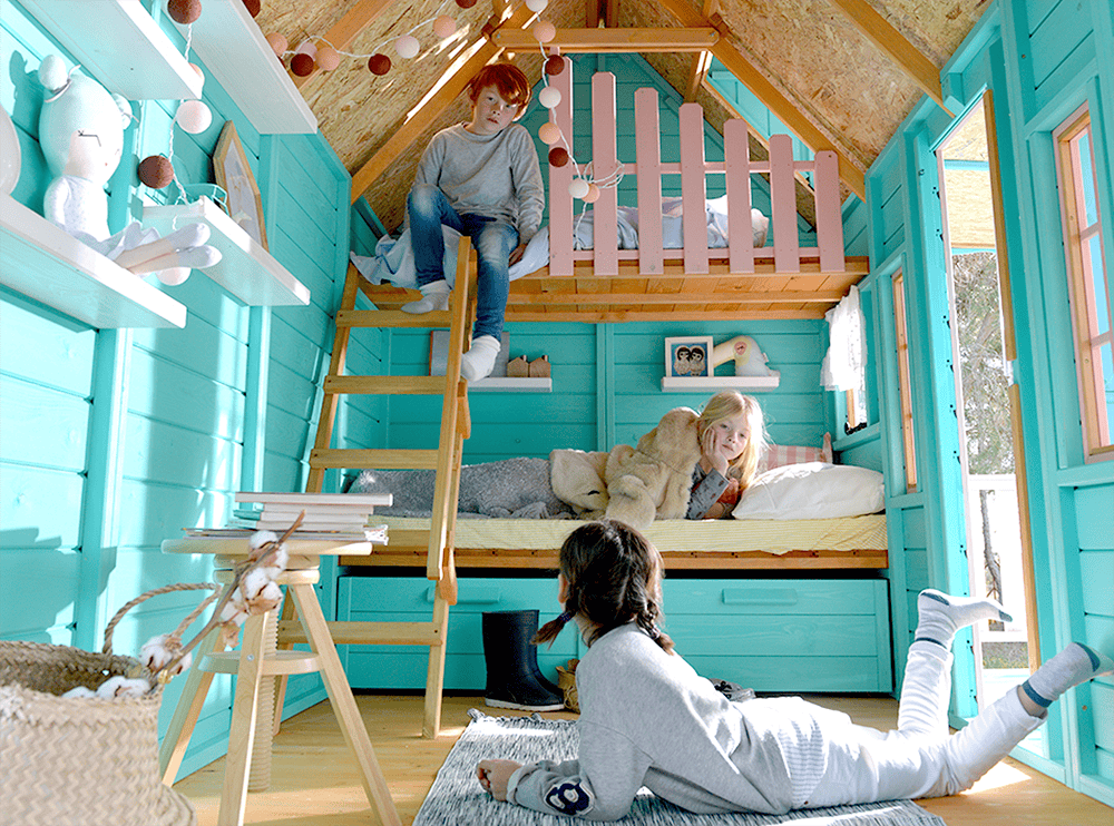 Kinder spielen in einer holzernen Spielhütte im Freien