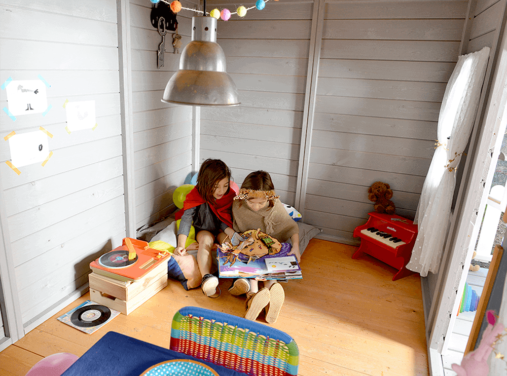 Kinder spielen in einer holzernen Spielhütte im Freien