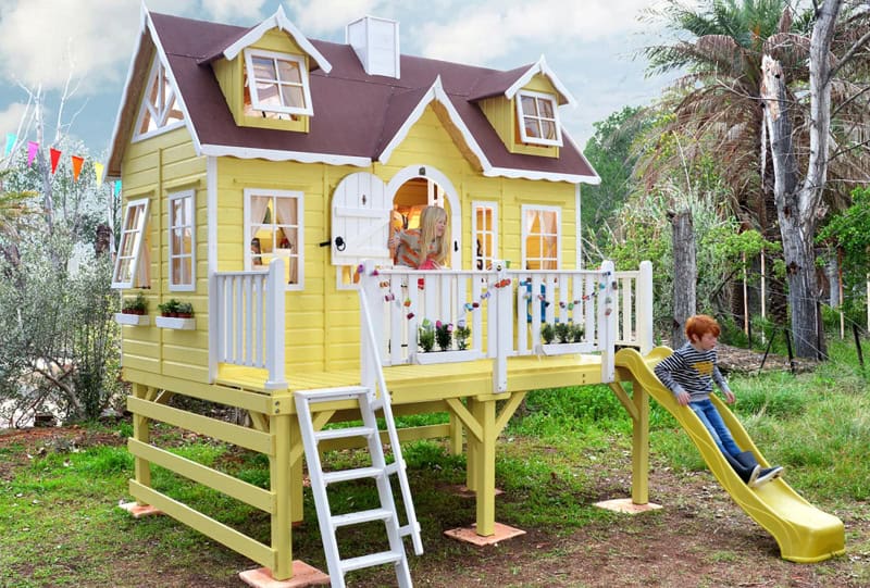 Kinder spielen in einer holzernen Spielhütte im Freien