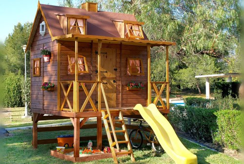 Kinder spielen in einer holzernen Spielhütte im Freien