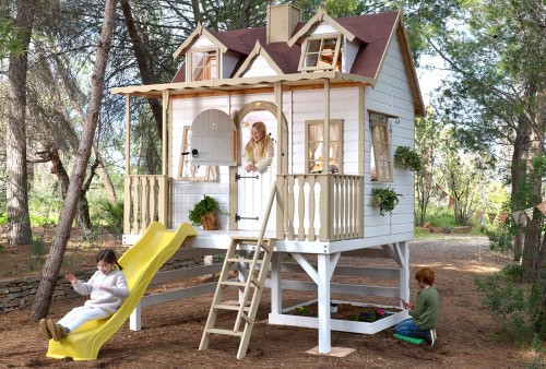 Kinder spielen in einer holzernen Spielhütte im Freien