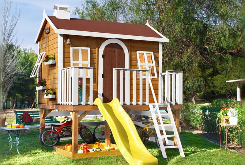 Kinder spielen in einer holzernen Spielhütte im Freien