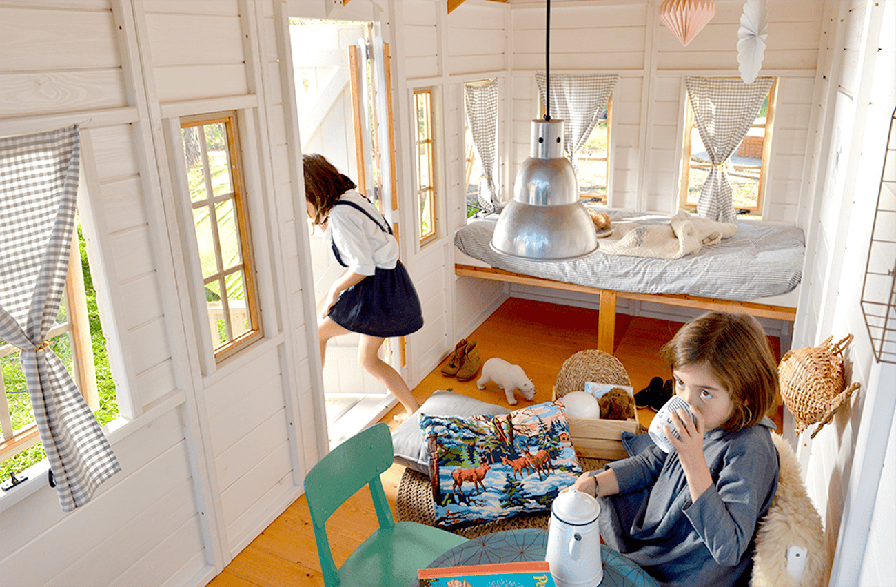 Kinder spielen in einer holzernen Spielhütte im Freien