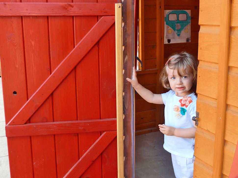 Kinder spielen in einer holzernen Spielhütte im Freien