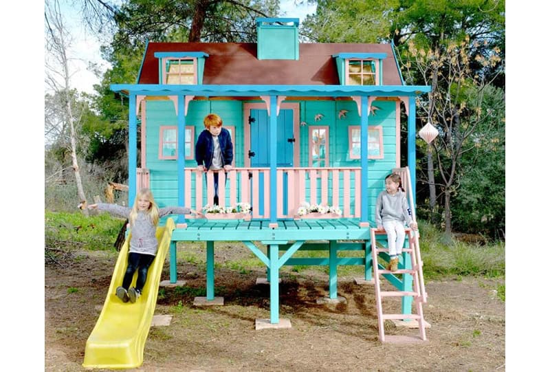 Kinder spielen in einer holzernen Spielhütte im Freien