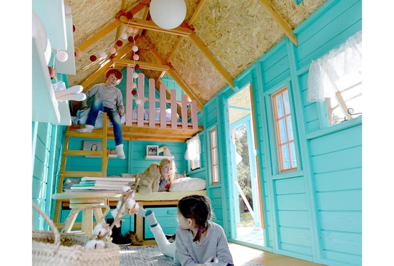 Kinder spielen in einer holzernen Spielhütte im Freien