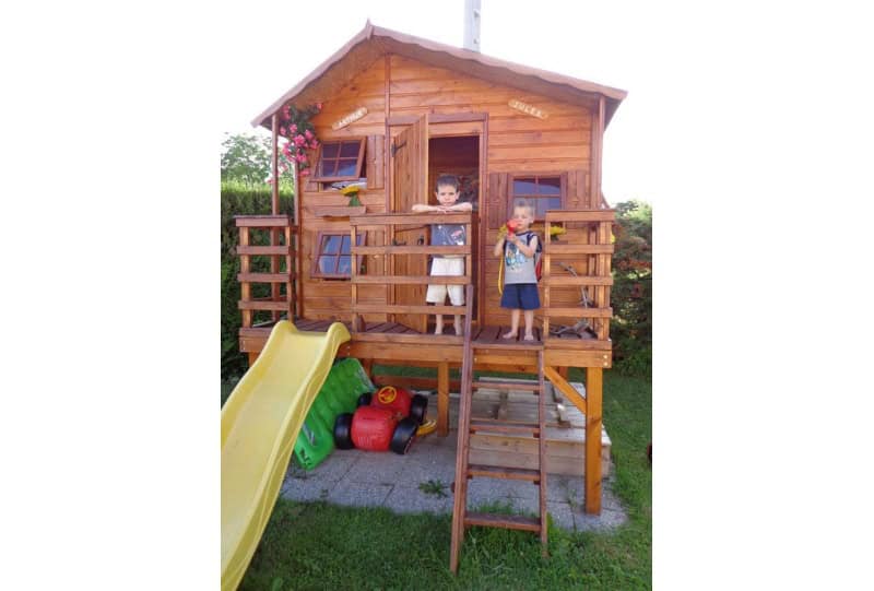 Kinder spielen in einer holzernen Spielhütte im Freien