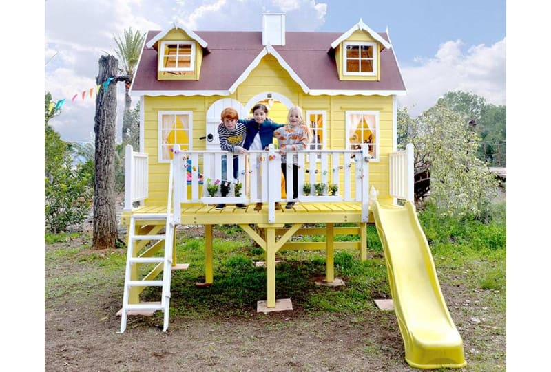 Kinder spielen in einer holzernen Spielhütte im Freien