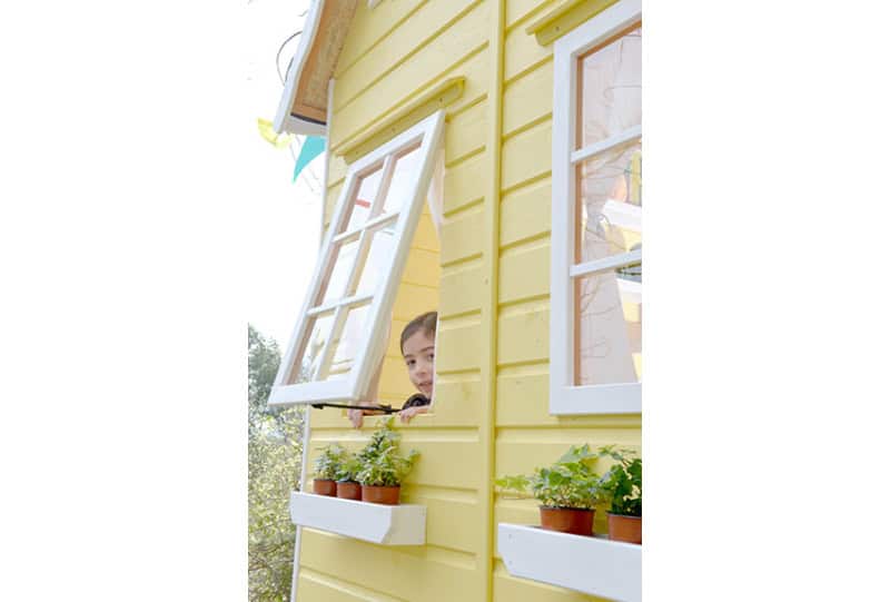 Kinder spielen in einer holzernen Spielhütte im Freien