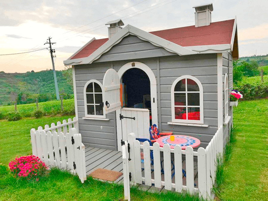 Kinder spielen in einer holzernen Spielhütte im Freien