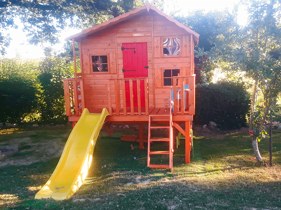 Kinder spielen in einer holzernen Spielhütte im Freien