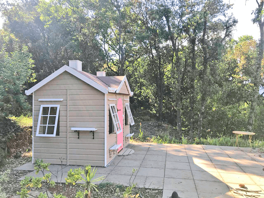 Kinder spielen in einer holzernen Spielhütte im Freien