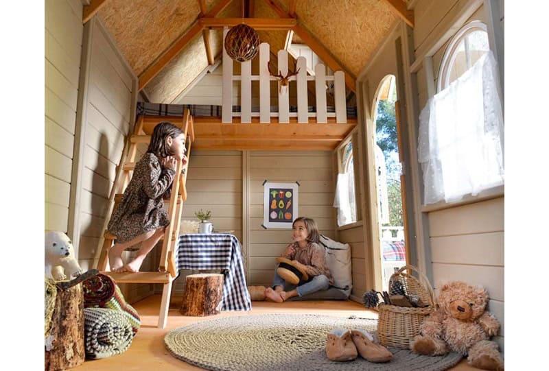 Kinder spielen in einer holzernen Spielhütte im Freien