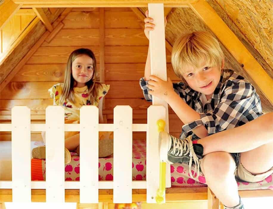 Kinder spielen in einer holzernen Spielhütte im Freien