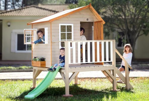 Kinder spielen in einer holzernen Spielhütte im Freien