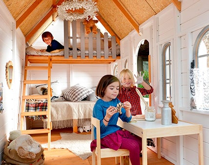 Kinder spielen in einem hölzernen Spielhaus im Freien