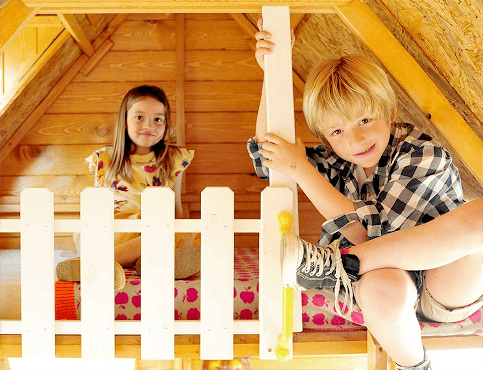 Kinder spielen in einem hölzernen Spielhaus im Freien