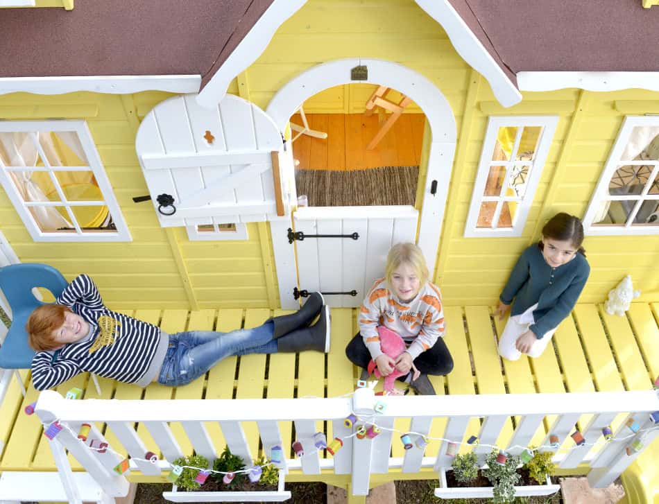 Kinder spielen in einem hölzernen Spielhaus im Freien