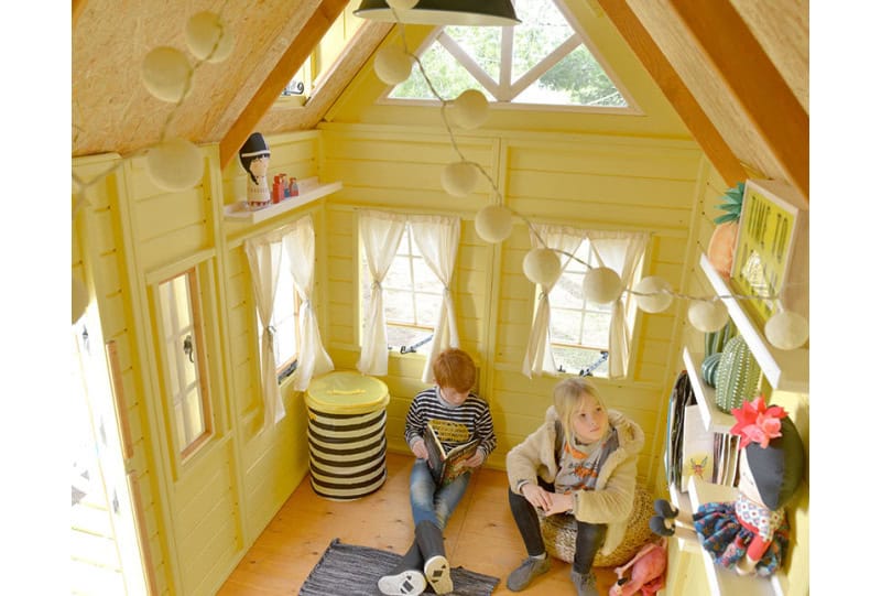 Kinder spielen in einem hölzernen Spielhaus im Freien