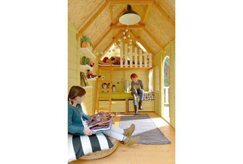 Kinder spielen in einem hölzernen Spielhaus im Freien