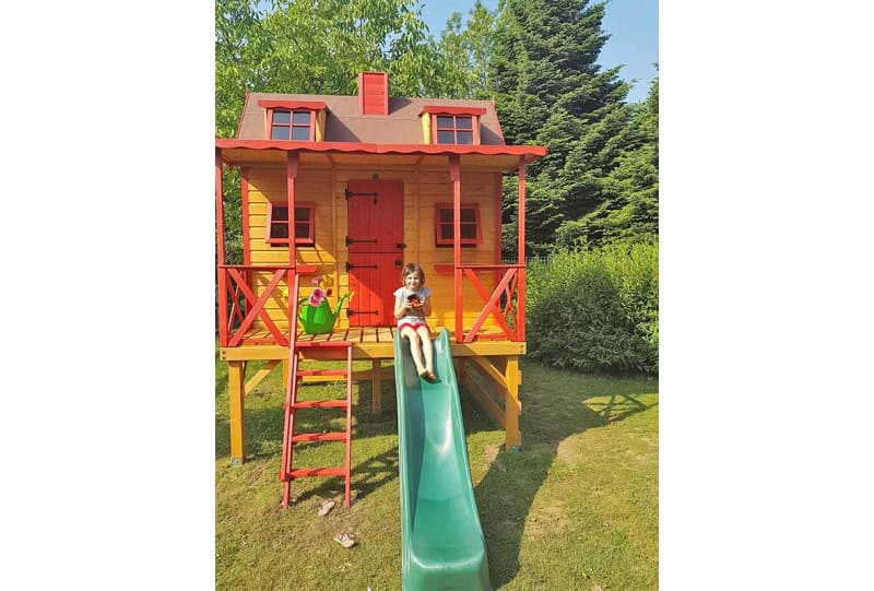 Kinder spielen in einem hölzernen Spielhaus im Freien