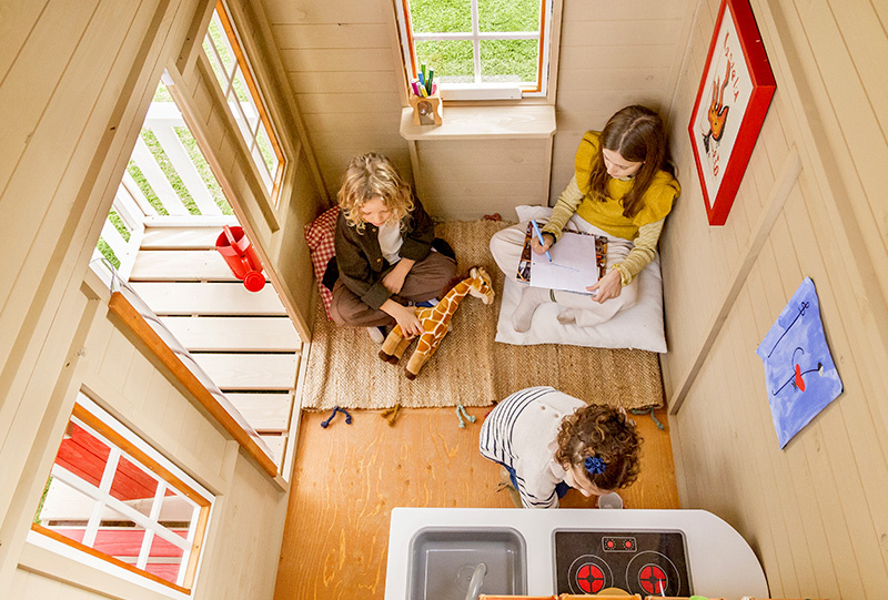 Kinder spielen in einem hölzernen Spielhaus im Freien