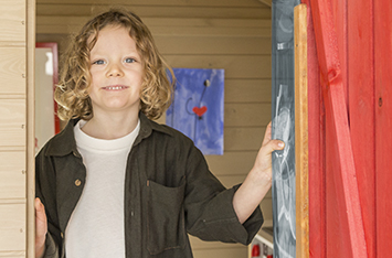 Kinder spielen in einem hölzernen Spielhaus im Freien