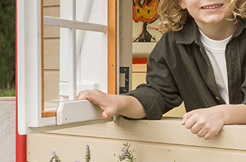 Kinder spielen in einem hölzernen Spielhaus im Freien