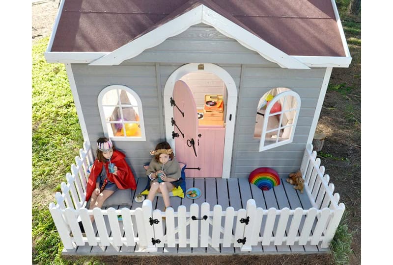 Crianças brincando em uma casinha de madeira ao ar livre